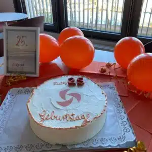 cimt Geburtstagskuchen auf einem Tisch, im Hintergrund orangene Luftballons